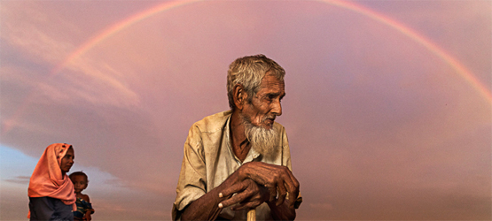 un anziano appoggiato al bastone con un arcobaleno