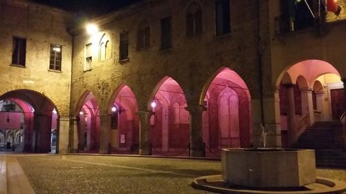 i portici del Broletto illuminati di rosa